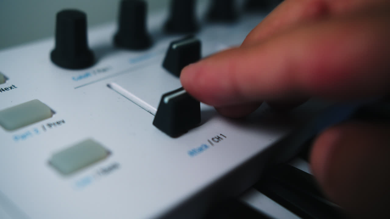 Close-up of a hand adjusting a knob on a synthesizer