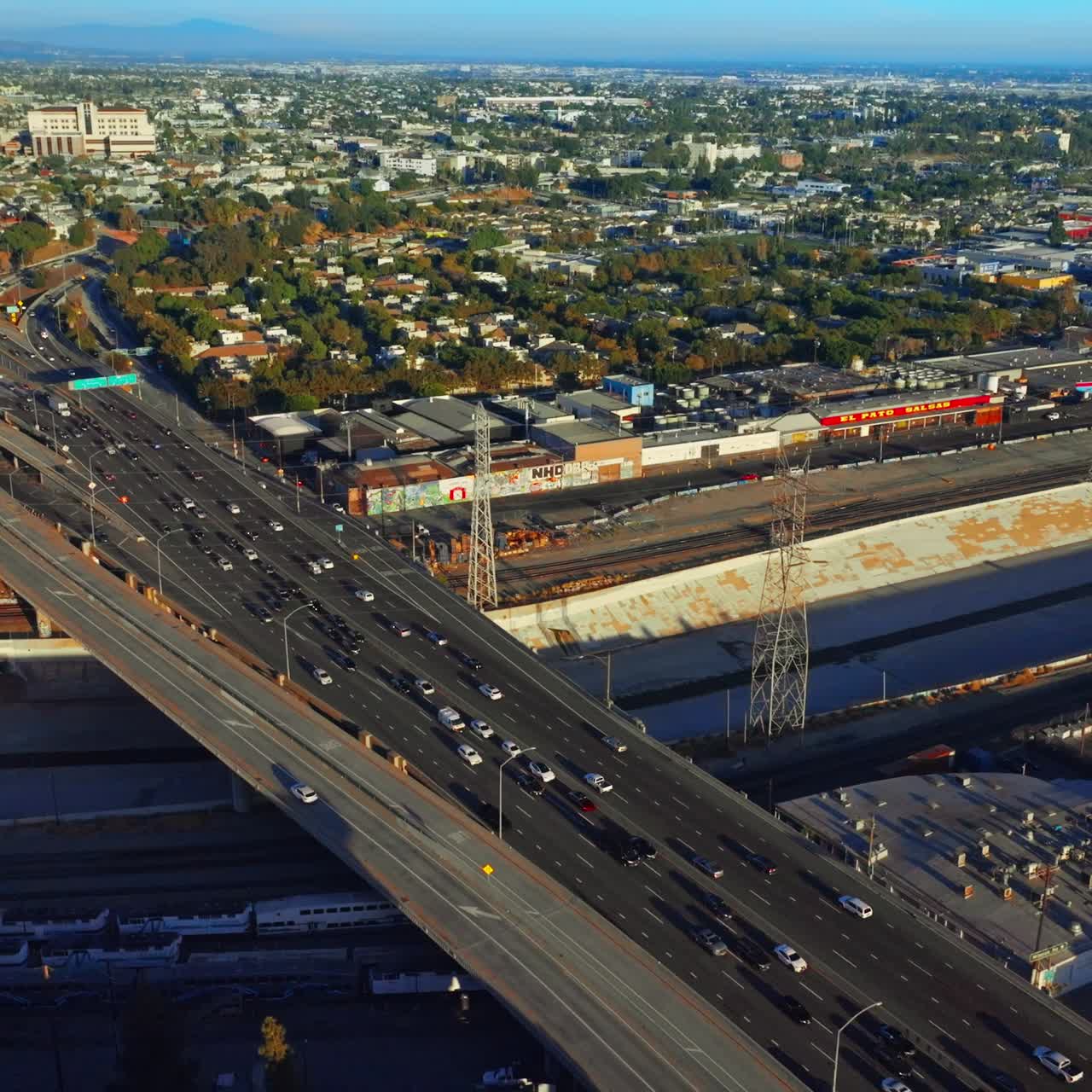 Sunny panorama of green Los Angeles. Drone rising above the busy traffic road with numerous cars. Top view