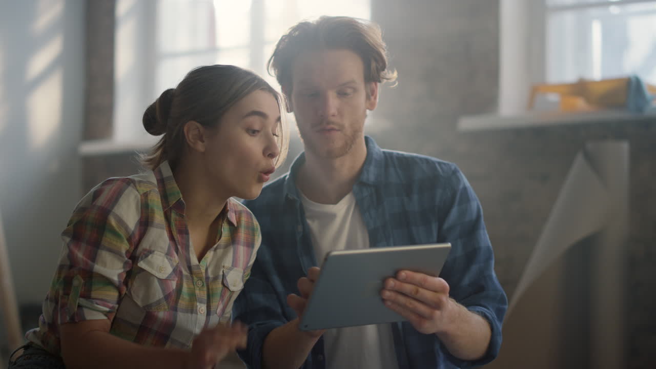 una pareja feliz discutiendo ideas de diseño en el interior. una mujer apuntando a la pantalla de la tableta.