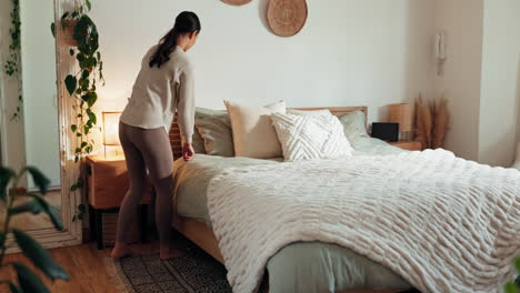 woman making a bed in a cozy bedroom