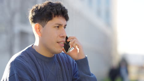 young latino man talking on phone outdoors