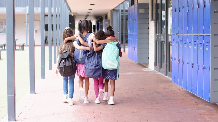 Un grupo de escolares con mochilas caminando juntos por el pasillo de la escuela.