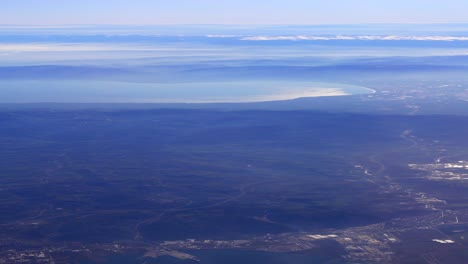aerial view of a mountainous region with a lake and city