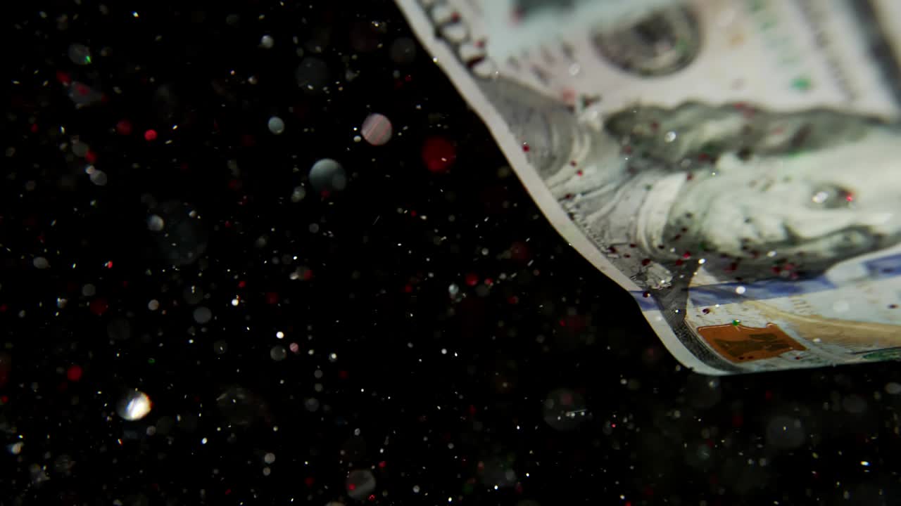 Falling flying american dollar banknotes and flying mixing with the glitter sparkles on a black background in 4K Loopable. High quality falling Dollar banknotes in 4K. Video is Loopable
