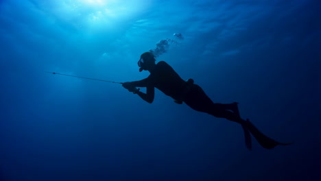silhouette of a freediver or spearfisher underwater