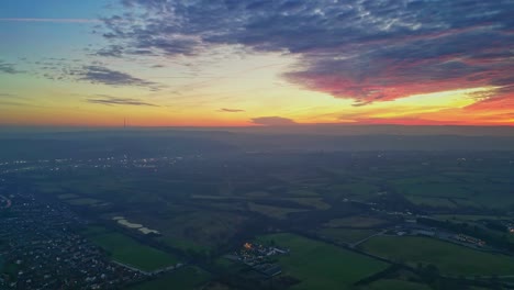 drone cinemática ciudad y campo paisaje verde campos brumosos colorido rojo puesta de sol horizonte nubes ardientes