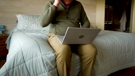 man practicing self-isolaton due to coronavirus tries to work from home while sitting on the edge of his bed - sliding movement with no face