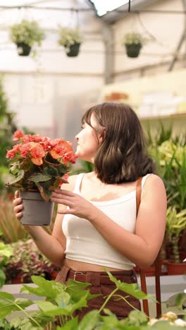 woman smelling flowers in a greenhouse. vertical