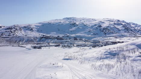 Aerial-view-of-small-town-by-frozen-lake-in-snowy-mountain-landscape