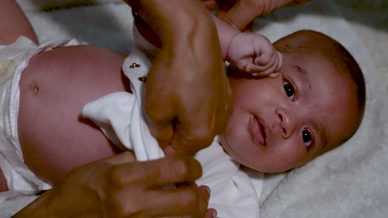 Adorable 2 Month Old Indian Baby Gently Getting Vest Put On By Hands Of Mother After Having Bath