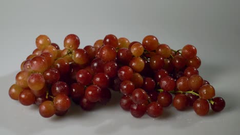 un racimo de uvas rojas sin semillas sobre una superficie blanca