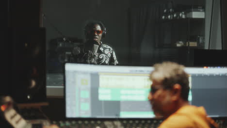 sound engineer and black singer recording song in music studio