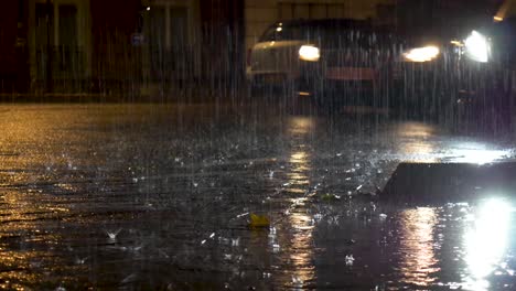 heavy rain on street pavement at night. car passing by.