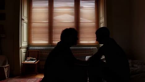 two silhouetted figures by a window