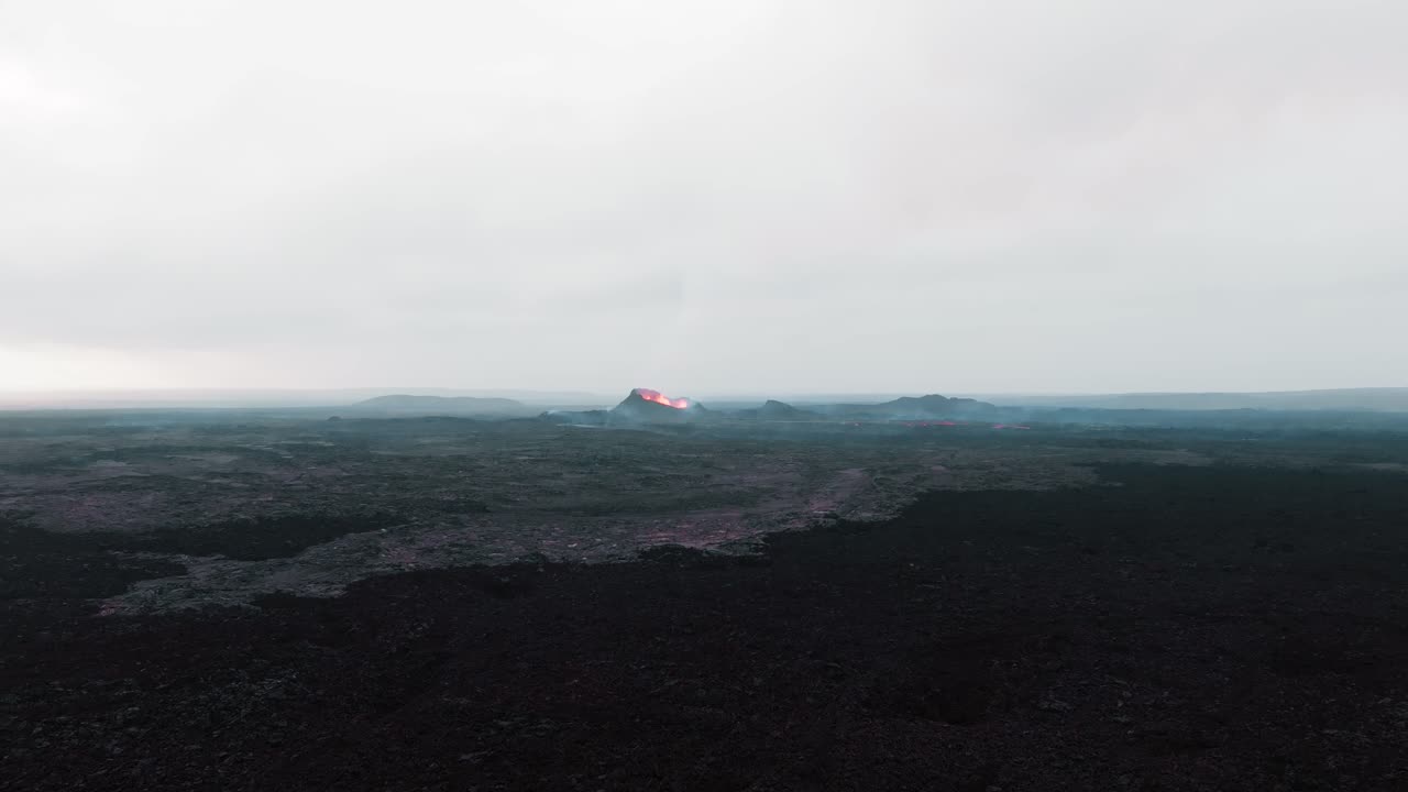 Aerial drone close up over the old dried up lava field and new eruptive crater of Sundhnukkar volcano