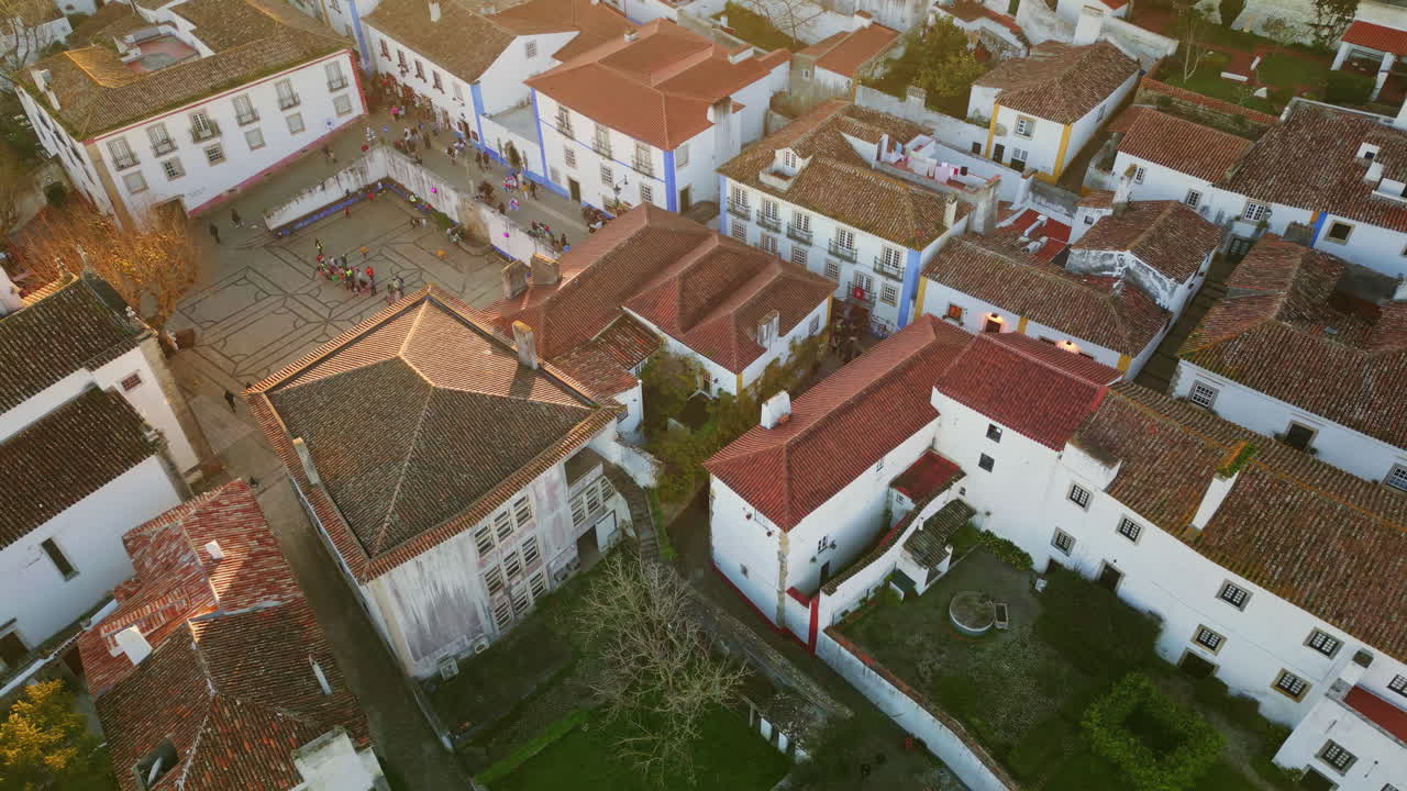Cozy suburban rooftops town buildings at evening aerial view. People walking