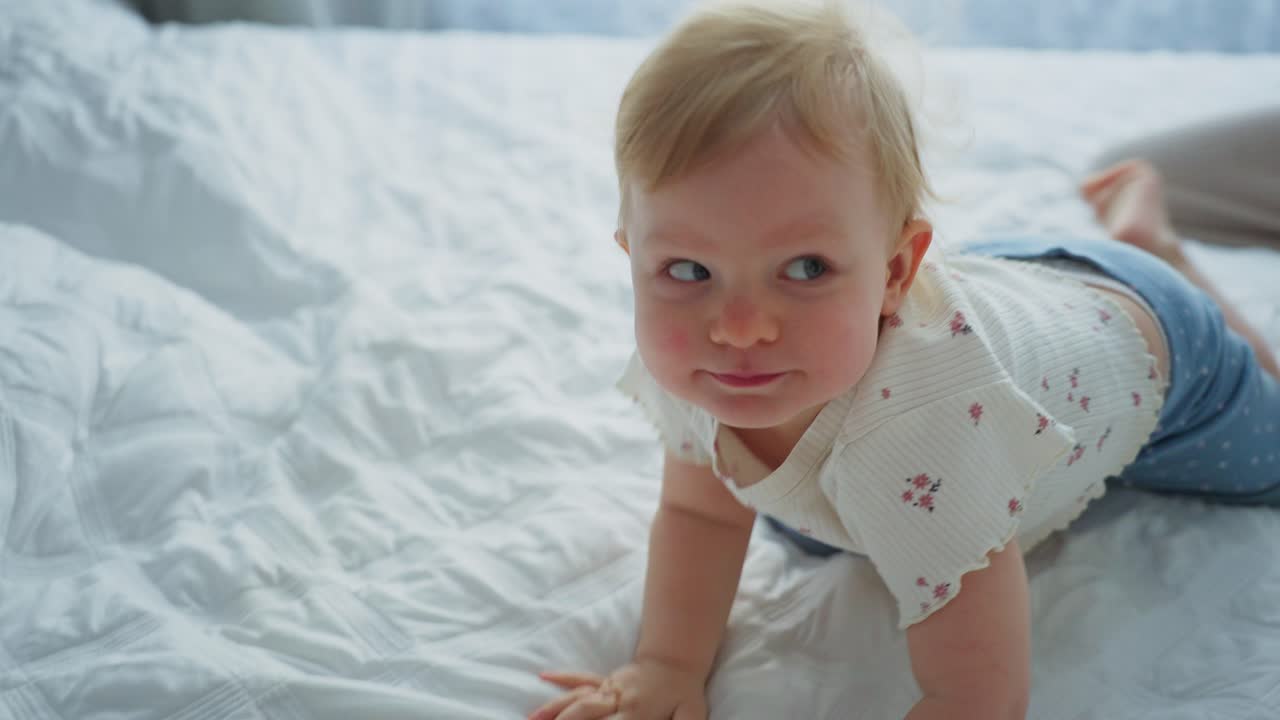 Glad baby leker med mor på hvit seng