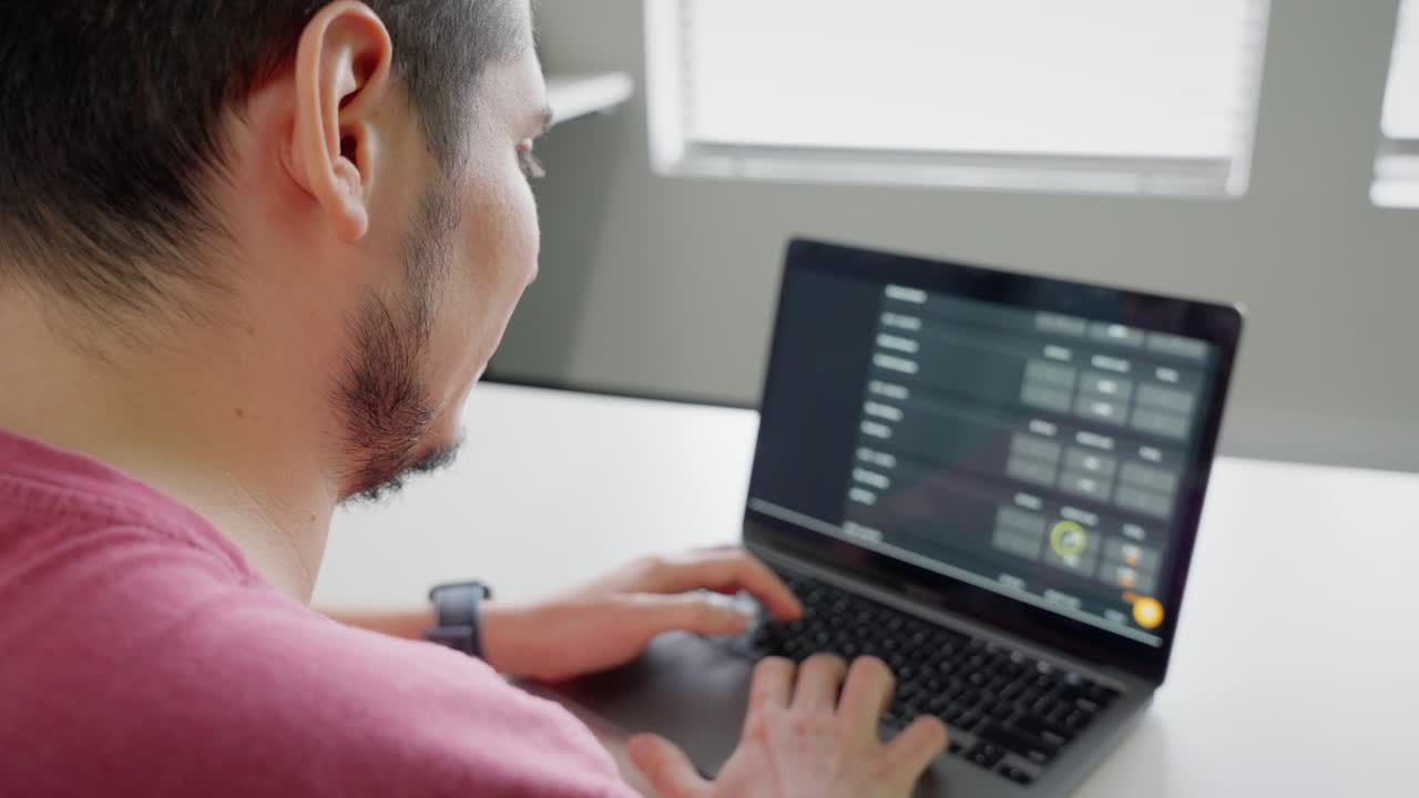 Over Shoulder View of Latin American Man Working on Technical Info on Laptop