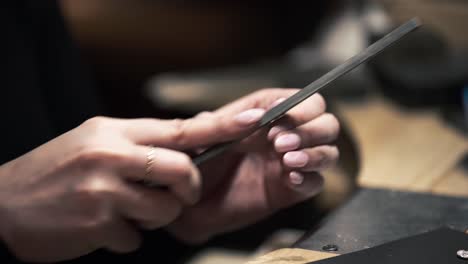 Shot-of-a-female-metalworker-filing-and-sanding-a-silver-metal-necklace