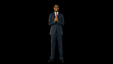 Businessman-standing-and-smiling-against-black-background