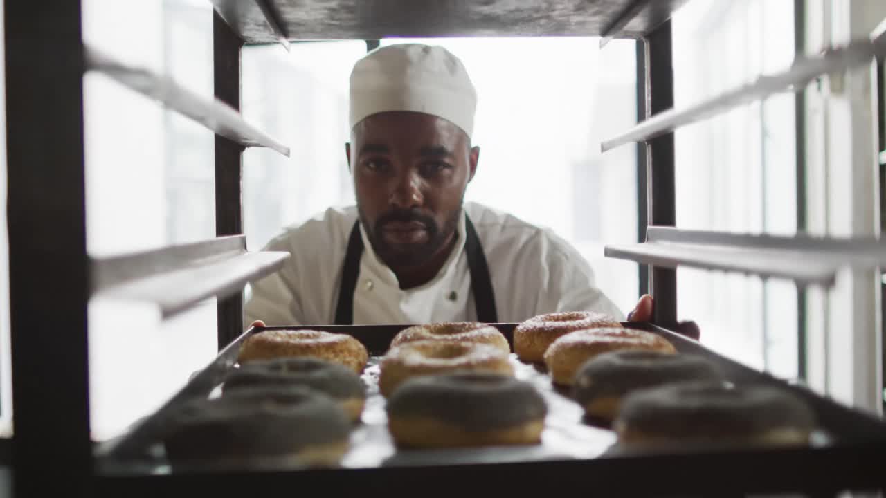 Animation of african american male baker checking freshly prepared doughnuts