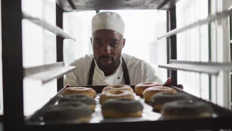Animation-of-african-american-male-baker-checking-freshly-prepared-doughnuts