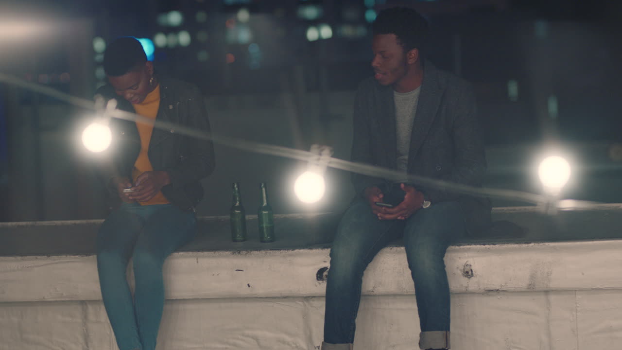 amigos jóvenes paseando por la azotea por la noche charlando disfrutando de la noche urbana hombre afroamericano coqueteando con una mujer hermosa en una cita riendo divirtiéndose