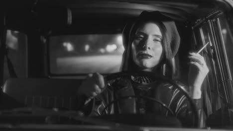 elegant woman smoking cigarette while driving vintage car on street at night