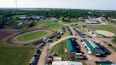 Aerial-pull-back-from-dirt-track-to-reveal-equestrian-centers,-builds-parking,-and-groomed-arena,-Kansas,-​Missouri