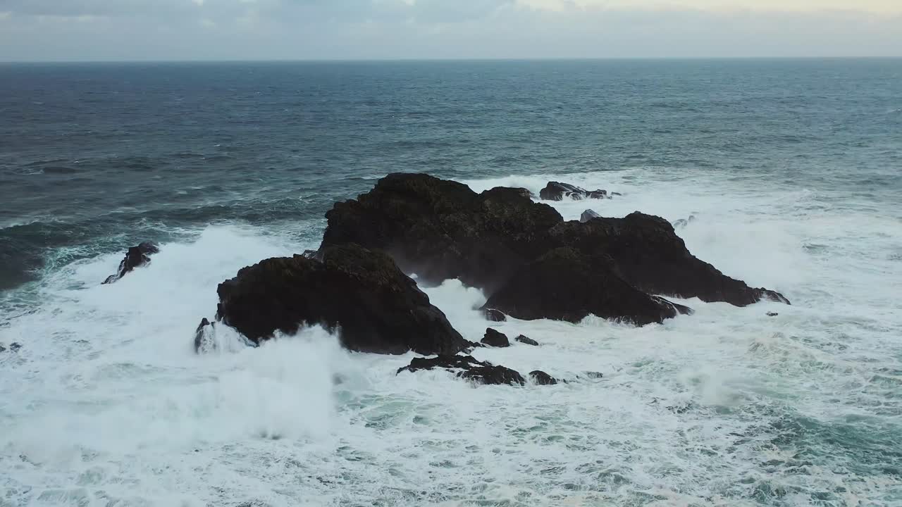 Inquadratura statica da drone di una piccola isola rocciosa nell'Oceano Atlantico durante una tempesta.