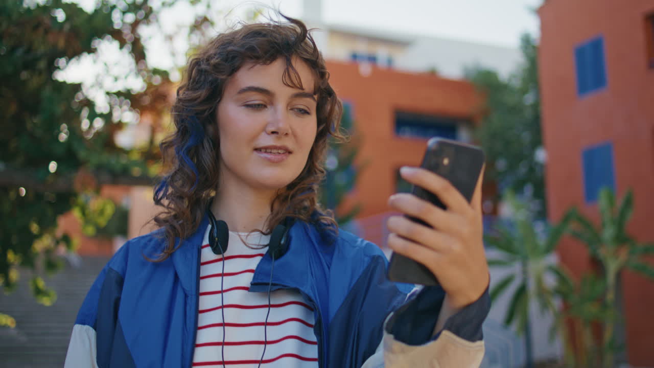 Primo piano di una ragazza alla moda in videochiamata con lo smartphone in una strada urbana. Donna che parla.