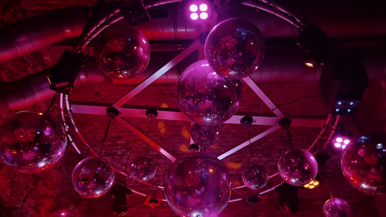 Multiple disco balls reflecting red and yellow lights in a Vienna nightclub