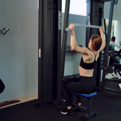 athletic girl performs vertical traction on the background of sports equipment near the mirror in the gym. healthy lifestyle
