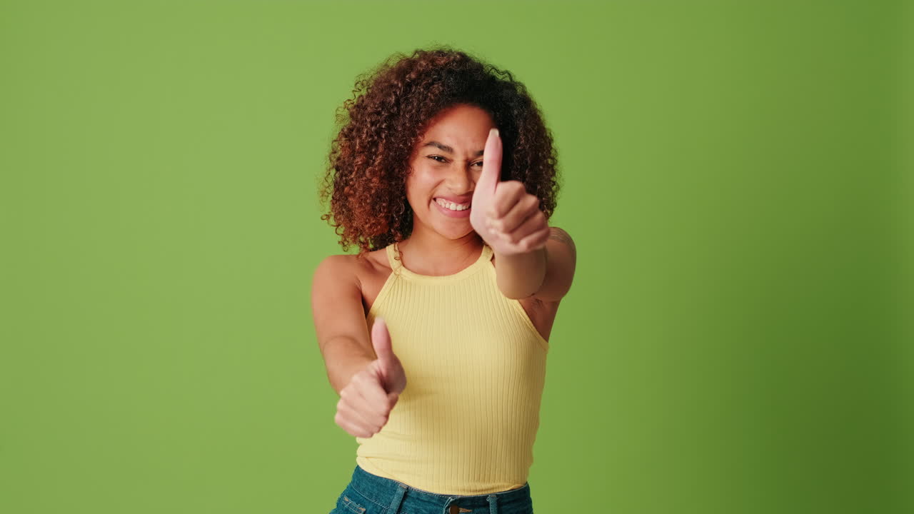 Smiling Young African American Woman Gives Thumbs Up and Points