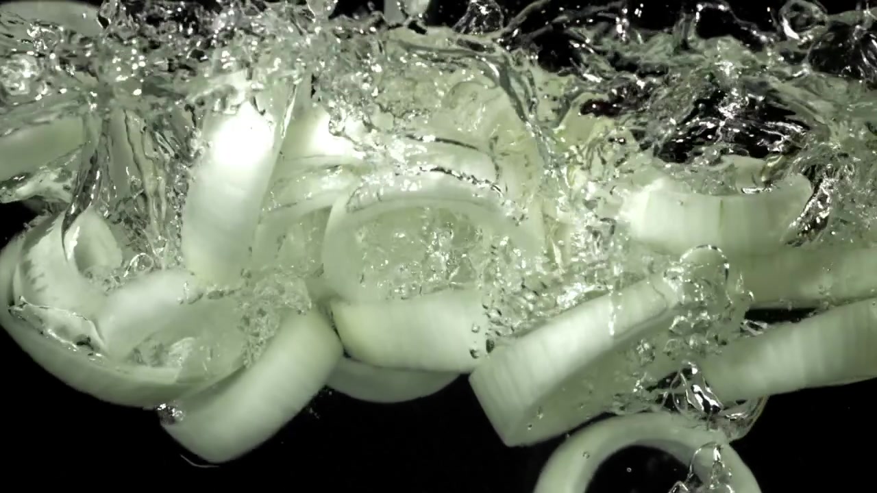 Fresh Onion Rings Dropping into Clear Water with Splashes