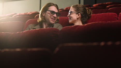 paar mit 3d-brille sitzt im kino, während sie sich unterhalten und einen film ansehen