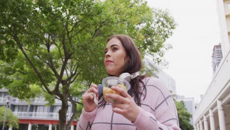 Young-Caucasian-woman-eating-and-walking