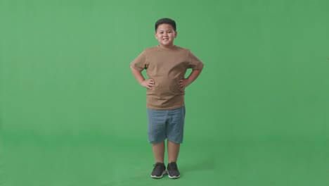 full body of asian boy warmly smiling on green screen background in the studio