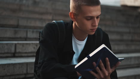 Young student writing notes outdoors.