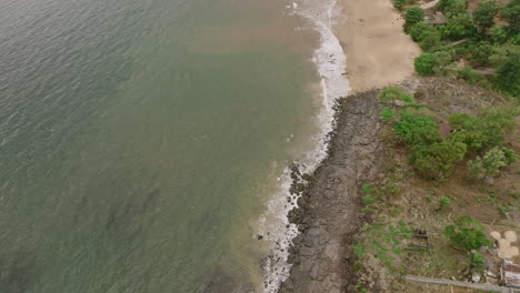 aerial footage of ocean waves crashing into the rocks and the beach on the coast of sierra leone