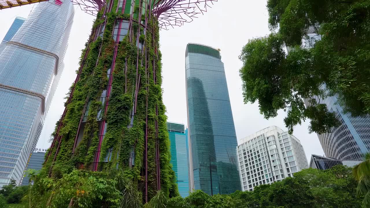 Green vegetation gracefully climbs a tower, creating a striking contrast against the backdrop of sleek, modern skyscrapers, symbolizing the harmonious integration of nature and urban development