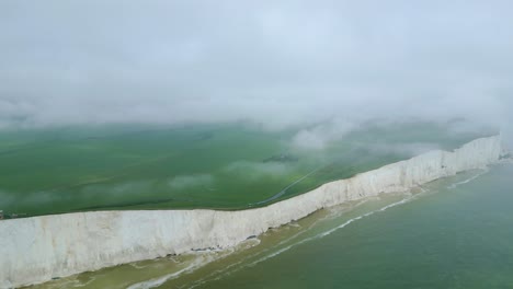 far view of belle tout lighthouse, white cliffs, green fields, cloudy sky, fog and sea taken with dji mini 3 pro drone in eastbourne england