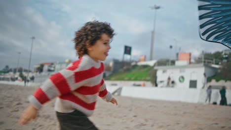 niño sonriente corriendo por la playa el fin de semana de otoño. niño juguetón disfrutando de las vacaciones