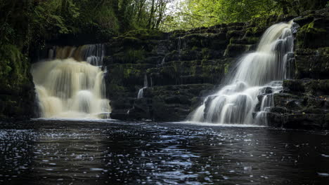 Lapso-De-Tiempo-De-La-Cascada-Del-Bosque-Primaveral-Rodeada-De-árboles-Con-Rocas-En-Primer-Plano-En-El-Paisaje-Rural-De-Irlanda