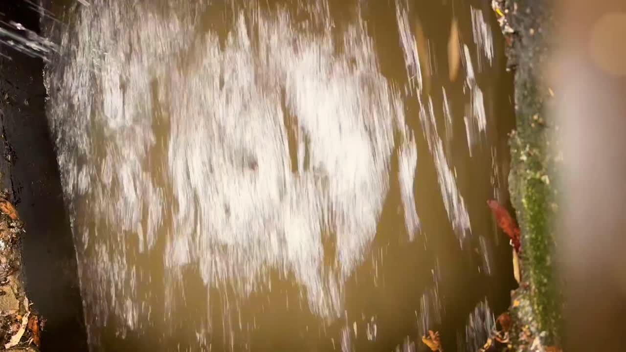 Experience the raw power of nature with this close-up of a muddy creek flowing rapidly after heavy rainfall. Perfect for projects depicting nature's force, flooding, or environmental themes