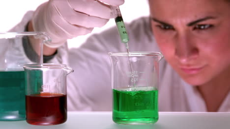 científico mezclando y inyectando líquidos en un vaso
