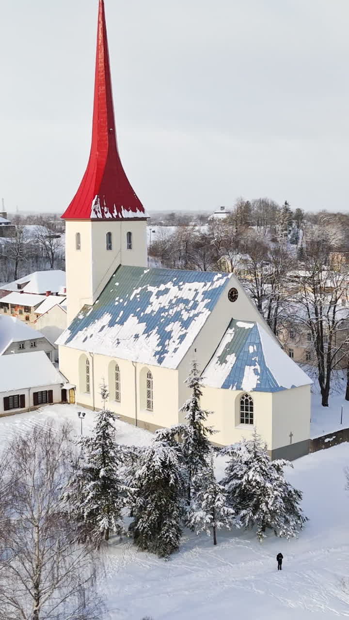 Vertical drone shot circling the snowy church, winter day in Rakvere, Estonia