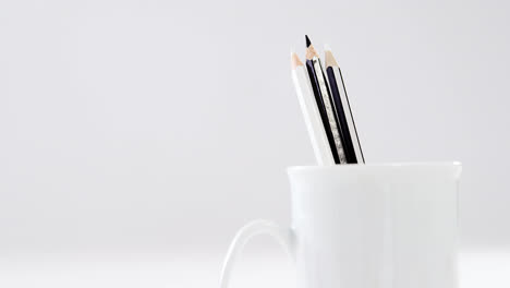 black and white colored pencils kept in mug on white background