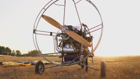 el parapente motorizado se encuentra en el campo al atardecer con una hélice de madera, y el piloto coloca el paracaídas y alinea las eslingas. preparación para el vuelo