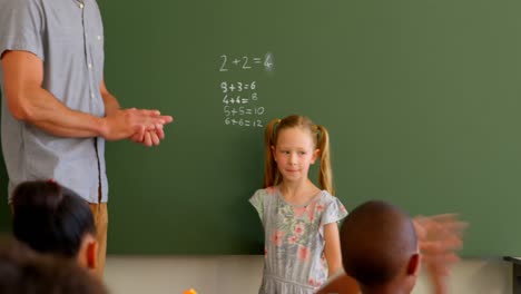 niños de la escuela aplaudiendo a la estudiante frente a la clase en el aula en la escuela 4k
